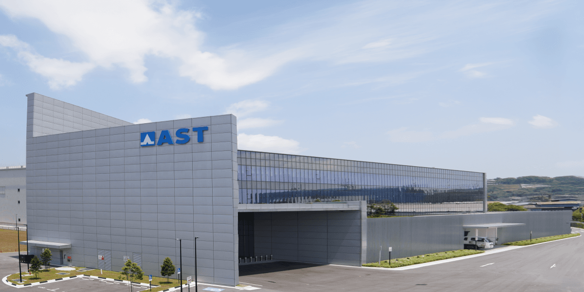 Exterior of the AST substrate plant in Singapore, a grey and glass industrial building with the AST logo on its facade