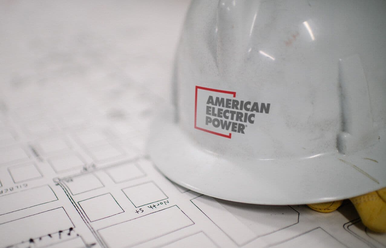 White American Electric Power hard hat with the AEP logo resting on a printed street-grid plan
