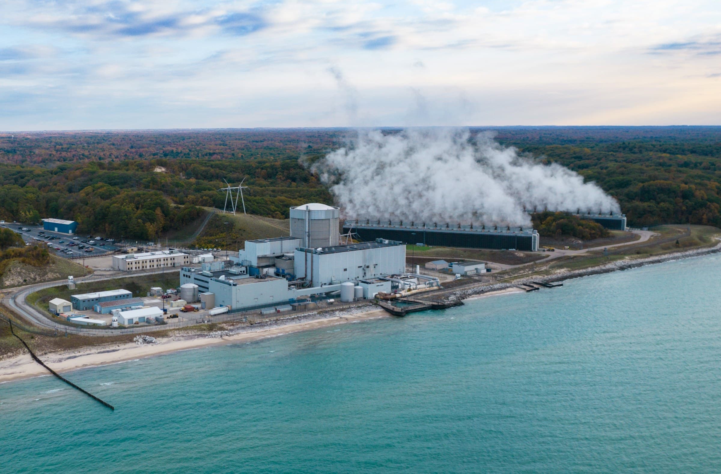 Aerial view of the Palisades nuclear plant on the shore of Lake Michigan, with steam rising from its cooling structure