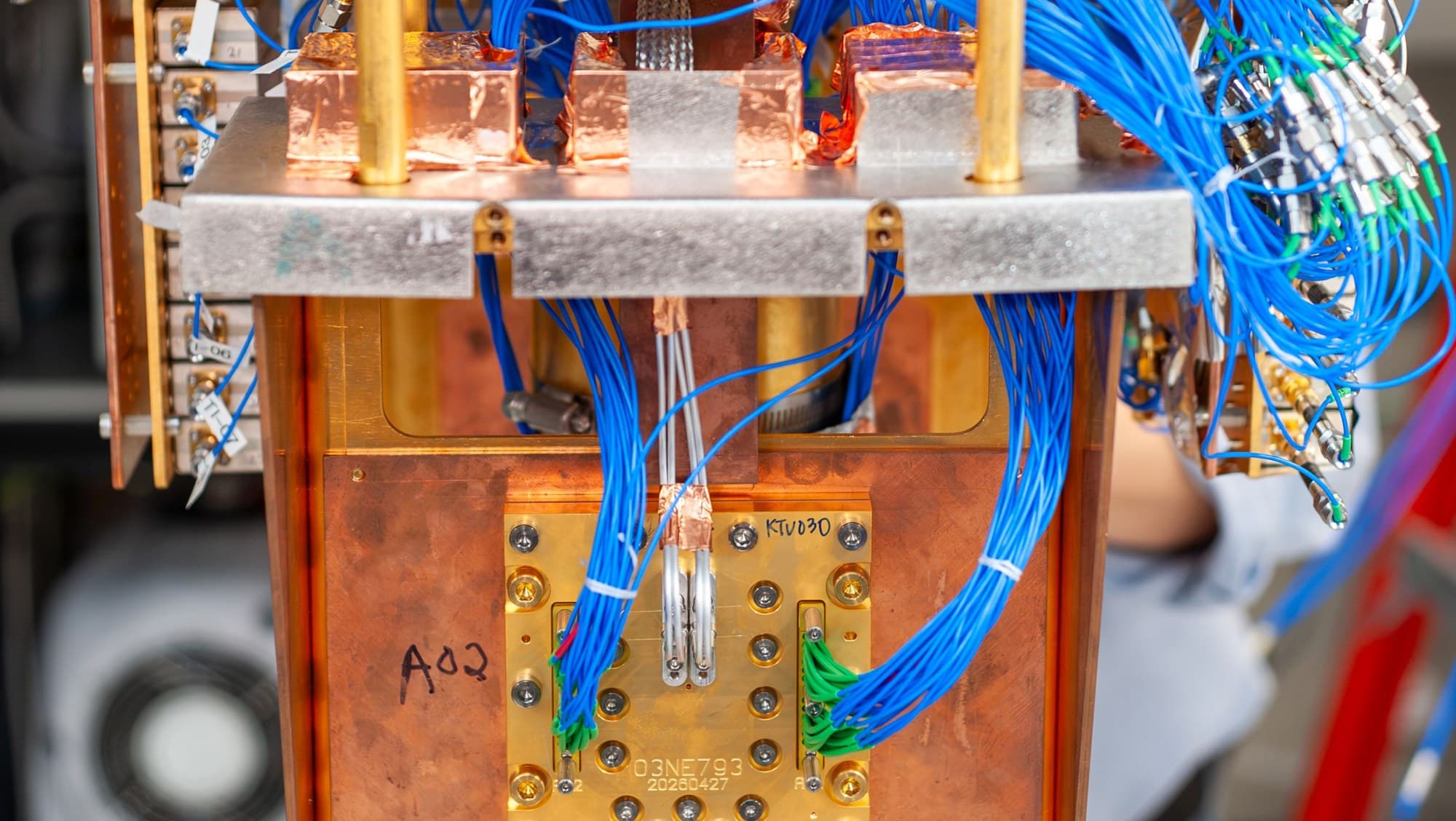 IBM Nighthawk quantum processor test setup with gold and copper cryostat plates and blue cabling