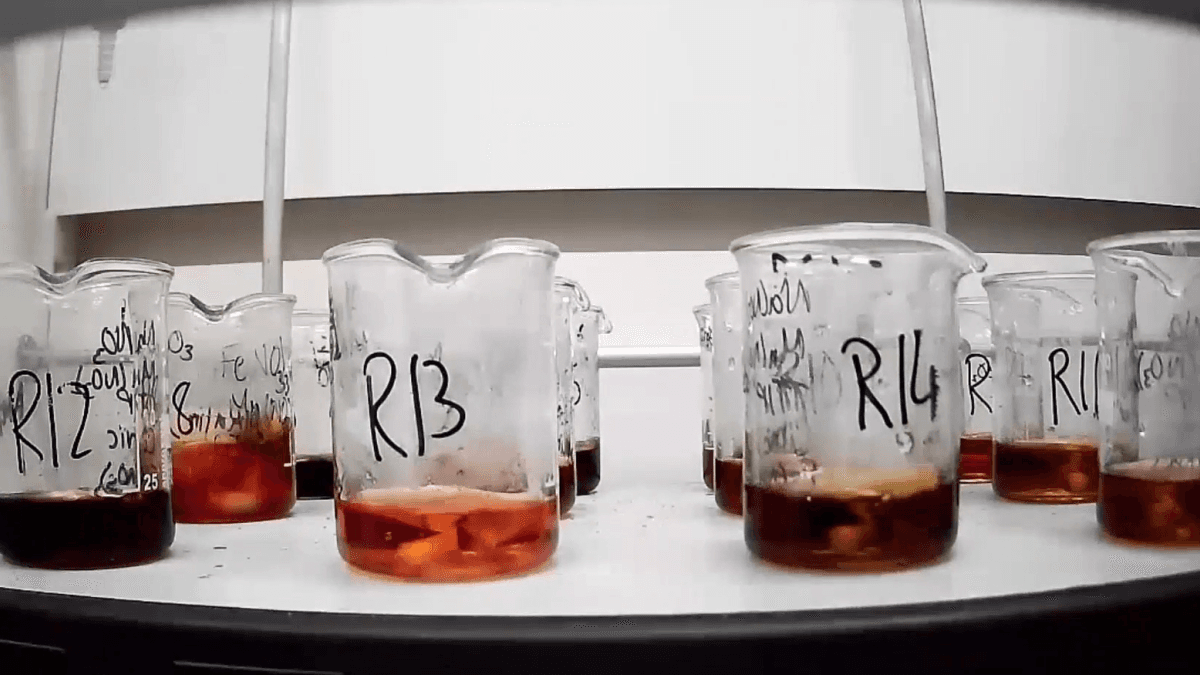 Labelled laboratory beakers holding different colour liquids, from the University of Surrey's sodium-ion cathode research release