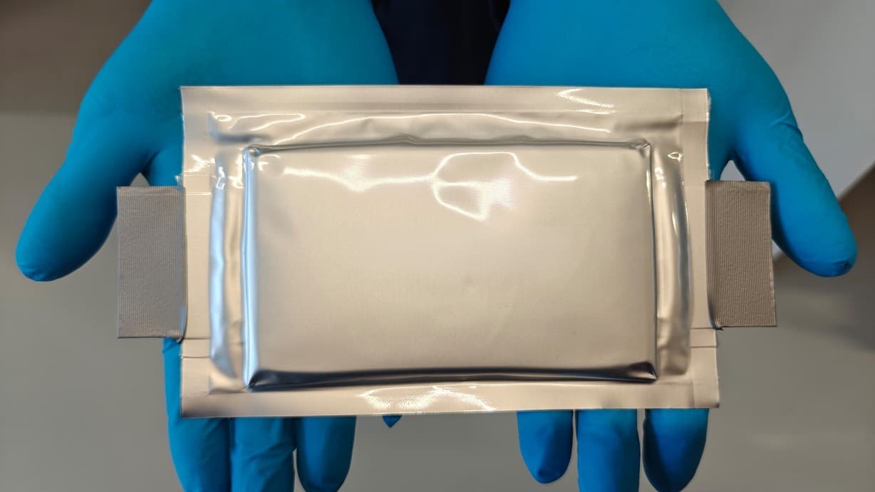 Gloved hands hold a silver pouch cell from the StrOboBatt project at Fraunhofer ISE