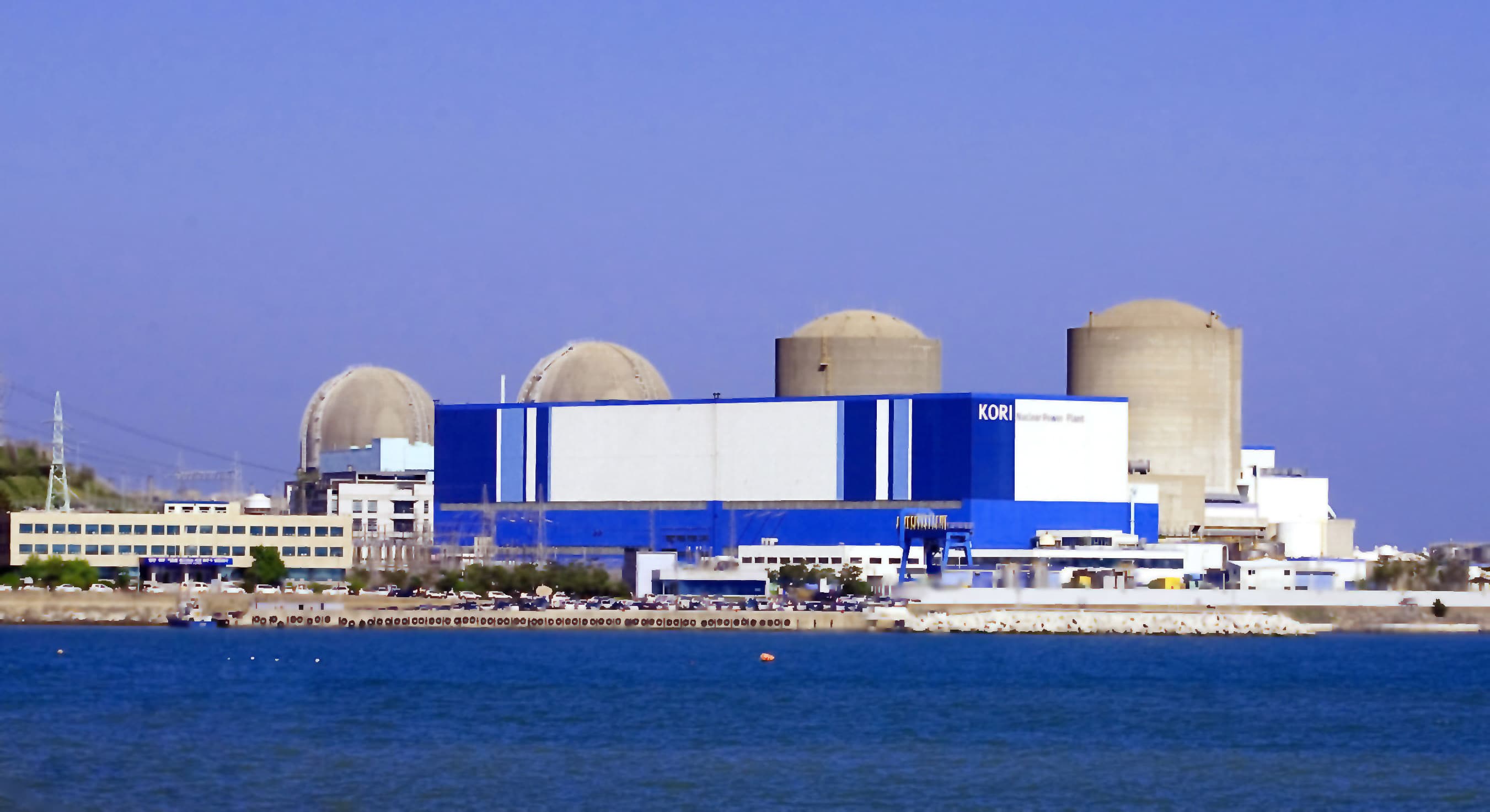 Kori nuclear power plant on the coast near Busan, South Korea, with four reactor containment buildings behind a blue-and-white turbine hall
