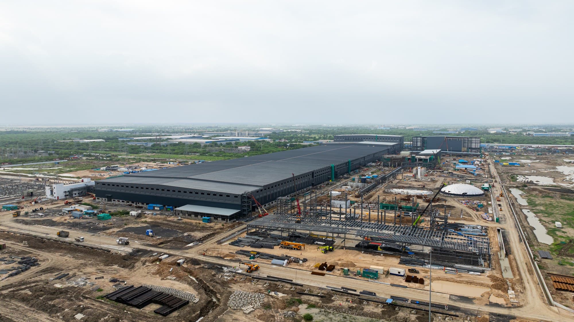 Aerial view of Agratas' battery plant under construction at Sanand, Gujarat, India, with the main factory hall and steel frames