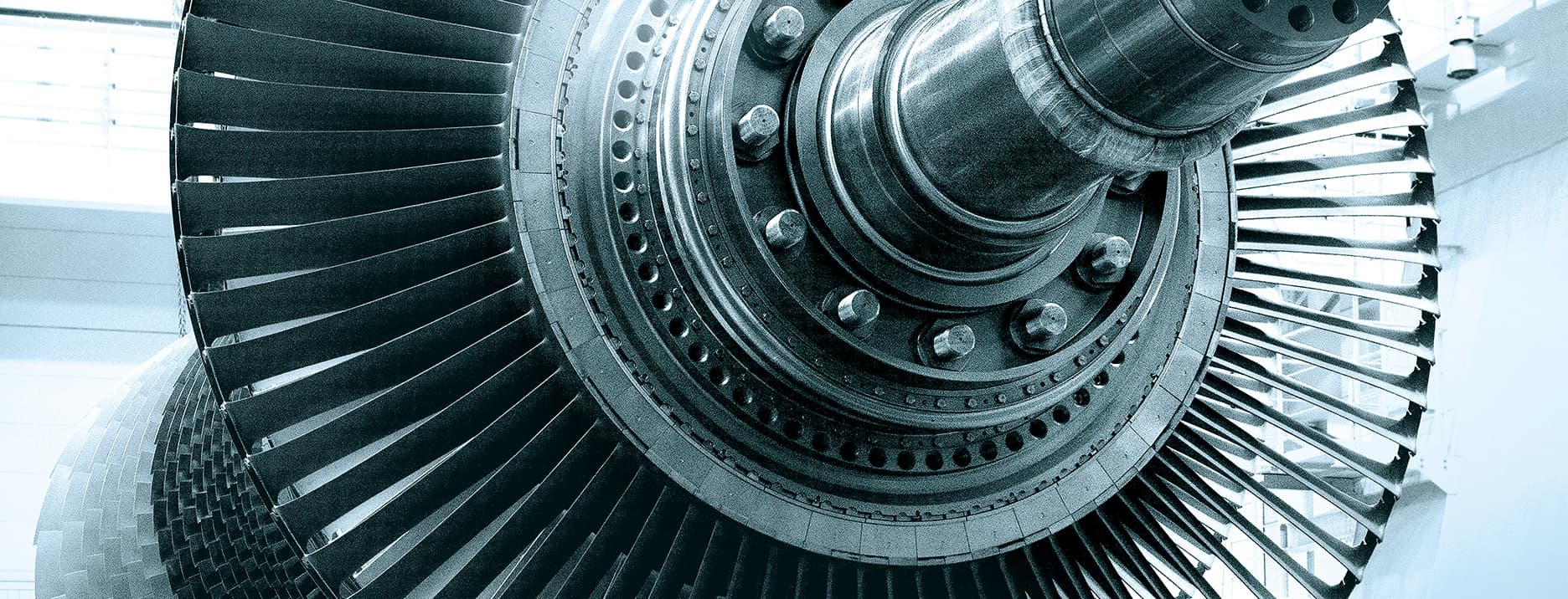 Gas turbine rotor with rows of compressor blades inside a plant hall, from Mitsubishi Power's gas turbine page