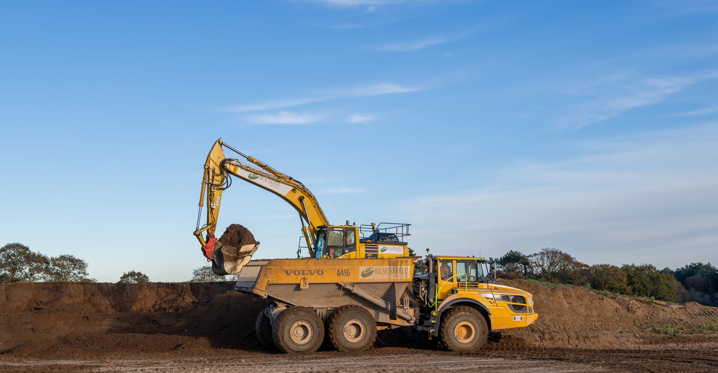 Excavator loading an articulated dump truck with earth at the Sizewell C construction site on the Suffolk coast