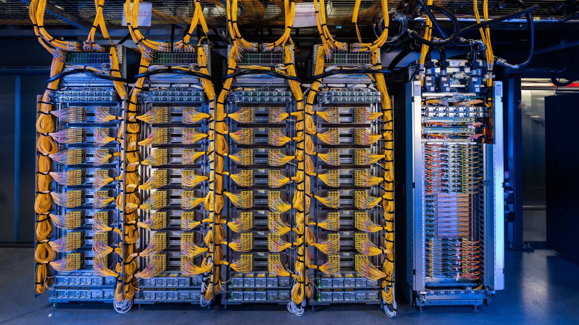 Rows of server racks wrapped in bundles of yellow fiber cabling in a data hall, image from NVIDIA's Google Cloud A5X blog post